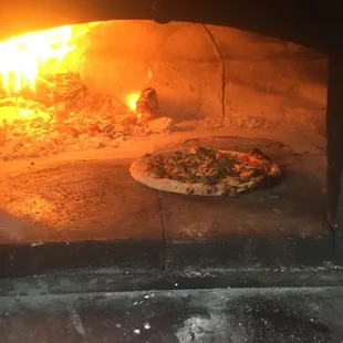 a pizza cooking in a brick oven