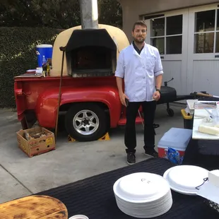 a man standing in front of a pizza oven