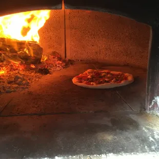 a pizza cooking in a brick oven