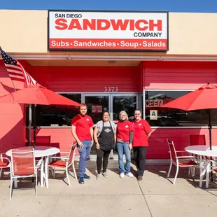 three people standing in front of a restaurant