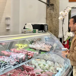 a man standing in front of a meat display