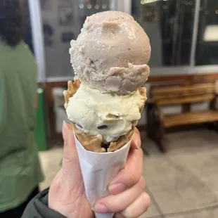 a hand holding a cone of ice cream