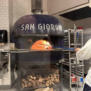 Pizza coming out by the third of three pizza crafters working this station.