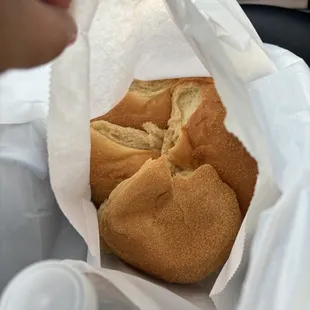 Fresh out of the oven pandesal in a white paper bag. They put a new plastic bag inside for you to put it in once it cools down.