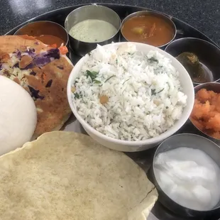 Coconut rice, idli, veggie uthapam, sauces, pickle, and dessert