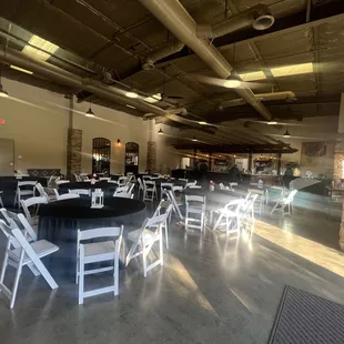 View of seating area inside tasting room. Tasting area in background. Room set up for a private party with overflow area in the back