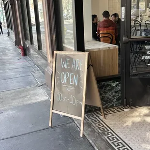 a sidewalk with a sign that says we are open