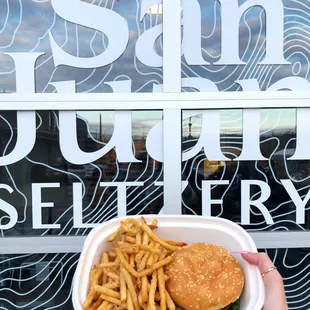 a hand holding a container of fries