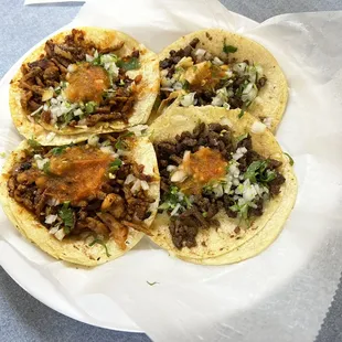 2 al pastor tacos on the left, and 2 carne asada tacos on the right.