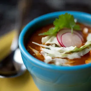 a blue bowl of soup on a yellow plate