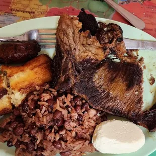 a plate of food with meat, rice, and beans