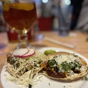 two tacos on a plate with a glass of beer