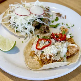 two tacos on a plate with a lime wedge