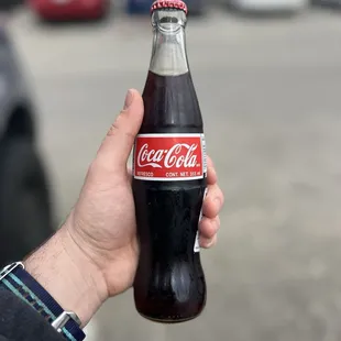 a hand holding a coke bottle