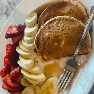  plate of pancakes, bananas, strawberries, and syrup
