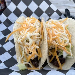 two tacos with shredded cheese and lettuce