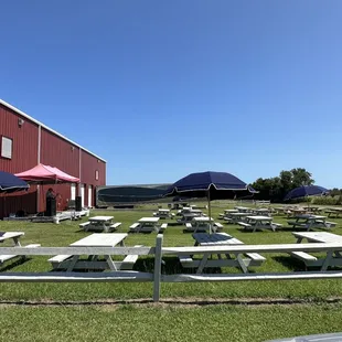 picnic tables and umbrellas in front of a red barn