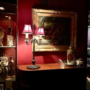 a table with a lamp and a painting on the wall