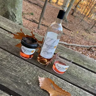 a bottle of wine and two glasses of wine on a picnic table