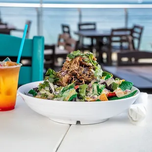 a bowl of salad and a drink on a table
