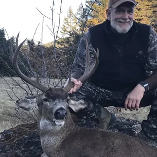 a man kneeling next to a deer