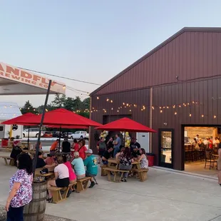 people sitting at tables under red umbrellas