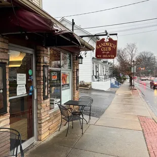 a sidewalk with tables and chairs