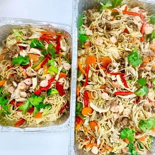 two takeout containers filled with noodles and vegetables