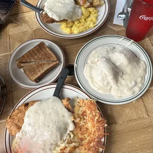 Chicken Fried Chicken and hash (bottom), Chicken Fried Steak Eggs with country potatoes (top) , biscuits &amp; gravy and wheat toast