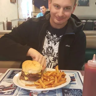 a man eating a hamburger and fries