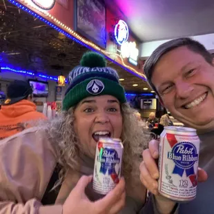 two people holding cans of beer