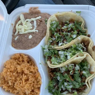 Three el pastor tacos, beans and rice.