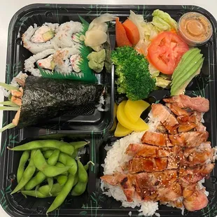 a bento tray with a variety of sushi