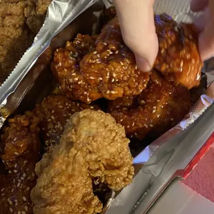 a person grabbing a piece of fried chicken