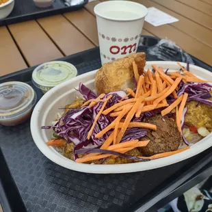 Curry bowl with rice, chicken korma, shredded veggies, samosa, potato cake. Tamarind and spicy green sauces.