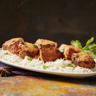 a plate of rice and chicken skewers