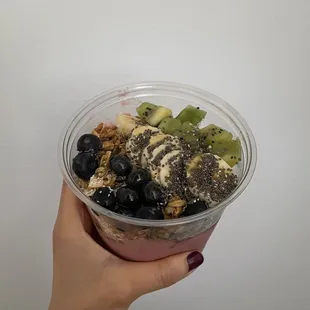 a hand holding a bowl of fruit