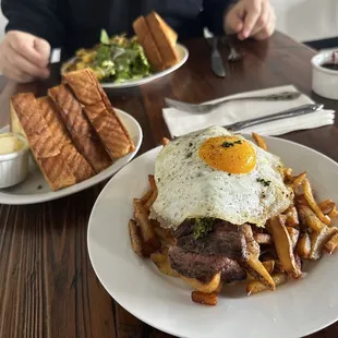 Steak and egg breakfast on a bed of fries.