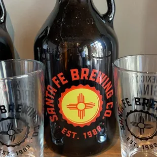 a growl of beer and two shot glasses