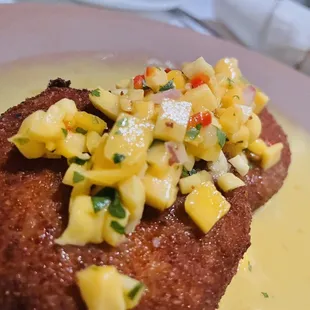 Crab cakes in a pineapple and mango sauce and topped on  a sweet corn slaw.