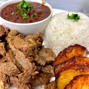 a plate of meat, rice, and a side dish