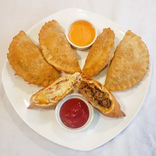a plate of empanadas with dipping sauce