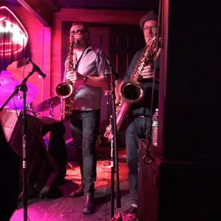 two men playing instruments in a dimly lit room