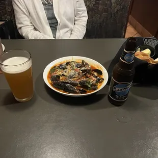 a woman sitting at a table with a bowl of pasta and a glass of beer