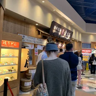 a group of people standing in line at a food court