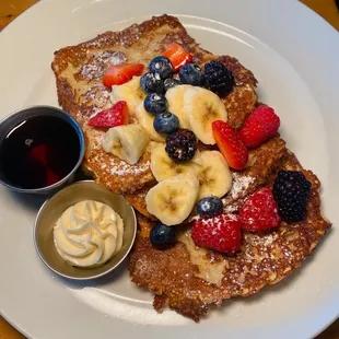 a plate of french toast topped with fruit and powdered sugar