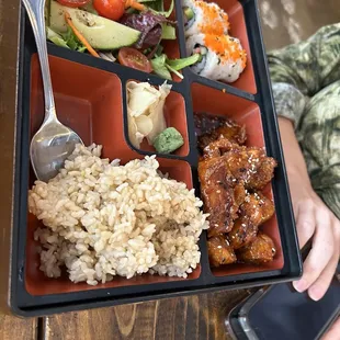 a person holding a cell phone and a tray of food
