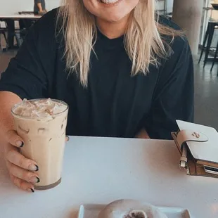 a woman holding a cup of coffee and a doughnut