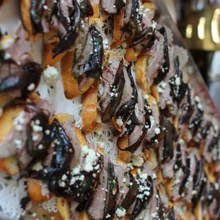 Tenderloin Crostini--garlic toast rounds topped with beef tenderloin, caramelized shallot balsamic reduction, and gorgonzola