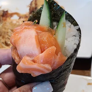 a hand holding a piece of sushi